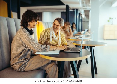 A dynamic scene of students collaborating and sharing ideas on a campus, enjoying the vibrant educational atmosphere with laptops and notes.