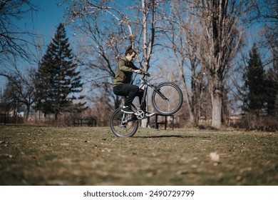 A dynamic scene of a young man effortlessly performing a wheelie on his bicycle in a beautifully lit park, capturing a moment of joy and freedom. - Powered by Shutterstock