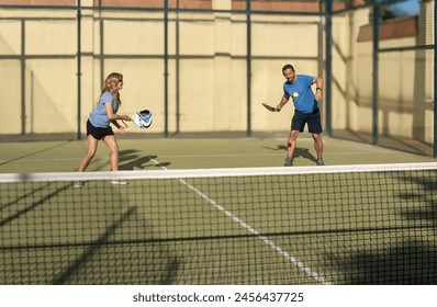 Dynamic shot of a middle-aged couple engaged in a spirited padel match, highlighting motion and coordination. - Powered by Shutterstock