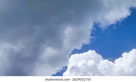 A dynamic sky featuring a contrast between dark, dramatic storm clouds and patches of bright blue sky with fluffy white clouds. Captures the beauty and power of changing weather.