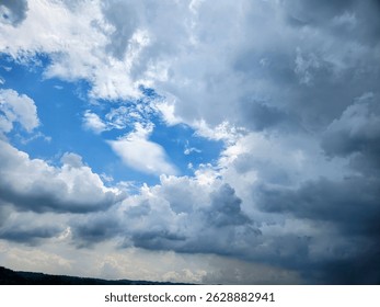 A dynamic sky filled with dramatic storm clouds and patches of blue, showing a weather transition over a distant treeline. A perfect visual for nature, weather, and background themes.