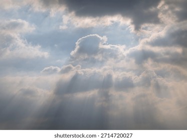 A dynamic sky filled with thick, dramatic clouds allows sunlight to stream through, creating beautiful rays of light and a moody atmosphere. Copy space.