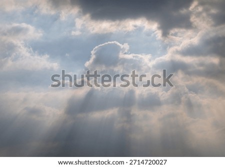 A dynamic sky filled with thick, dramatic clouds allows sunlight to stream through, creating beautiful rays of light and a moody atmosphere. Copy space.