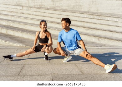 Dynamic stretching session between two fitness enthusiasts at a modern urban staircase during an early morning workout routine