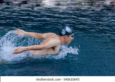 dynamic and swimmer in cap breathing performing the butterfly stroke