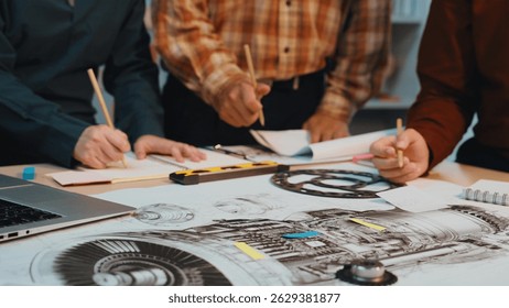 A dynamic team collaborates on technical drawings and engineering designs using laptops and tools, showcasing creativity and innovation in a modern office setting. SACTR