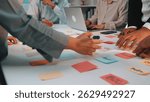 Dynamic team collaboration session featuring hands arranging colorful sticky notes on a table, showcasing creativity and strategic planning in a modern office environment. SACTR
