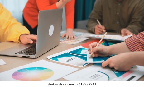 A dynamic team of creative professionals collaborates in a modern office space, analyzing marketing strategies and discussing design elements with various tools and documents. SACTR