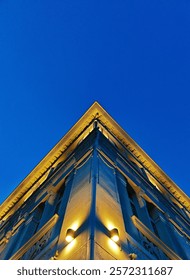A dynamic view of a building corner captured from above, set against a vibrant blue sky, showcasing modern architecture and a sense of elevation.