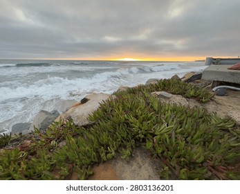 Dynamic view of ocean waves crashing and breaking into the large rocks of a riprap shoreline in Carlsbad, California.