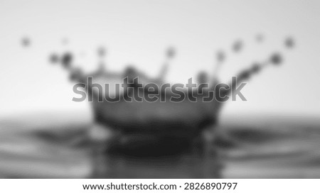 A dynamic water splash forms an abstract crown shape with droplets frozen in motion against a light background.