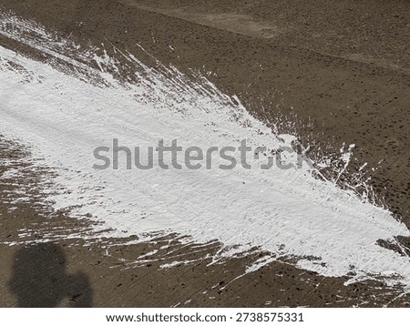Dynamic White Paint Splash Texture on Dark Gray Concrete Pavement Background Featuring Abstract Splatters and Messy Drops