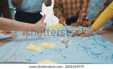 A dynamic workshop scene showcasing multiple hands engaged in writing and planning on a large paper with sticky notes, highlighting teamwork and creative thinking. SACTR