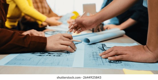 A dynamic workspace setting showcasing individuals actively engaged in project discussions around architectural blueprints, highlighting teamwork and creativity in design. SACTR