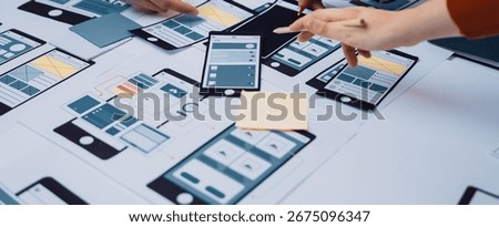 A dynamic workspace showcasing a collaborative app design process, featuring hands engaged with sketches, prototypes, and project notes on a table, highlighting teamwork and creativity. SACTR