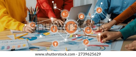 A dynamic workspace showing hands engaged in collaboration over business plans, with a laptop and orange icons illustrating focus and technological integration in strategy discussions. Amity