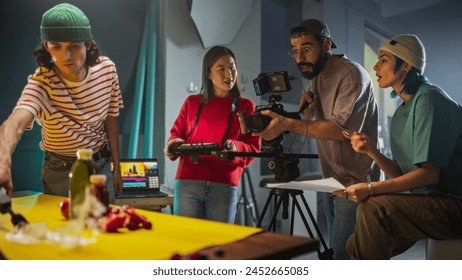 Dynamic Young Film Crew Engaged In A Lively Discussion On A Colorful Set, With A Female Asian Cinematographer Adjusting A Camera As Her Diverse Team Collaborates On A Creative Video Production Project - Powered by Shutterstock