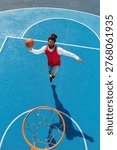 Dynamic young man leaps to make an impressive shot on a vibrant blue basketball court.