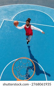 Dynamic young man leaps to make an impressive shot on a vibrant blue basketball court.