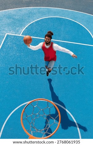 Dynamic young man leaps to make an impressive shot on a vibrant blue basketball court.