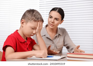 Dyslexia problem. Annoyed mother helping son with homework at table indoors, selective focus - Powered by Shutterstock