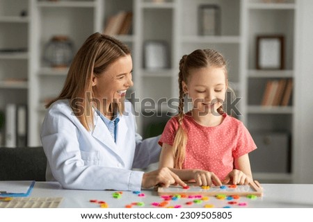 Dyslexia Treatment. Pediatric Neurologist Lady Having Therapy Session With Cute Little Girl, Smiling Female Child Making Word With Colorful Letters On Table, Improving Reading Skills, Closeup