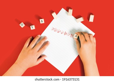 Dyslexia Word Stamped By Kids Hand On Ruled Paper With Red Ink On Red Background, Reading Difficulty Awareness And Disorder Cliche Concept. Education And Neurology With Copy Space