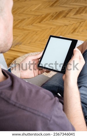 E book mockup on e reader in hands at home. Man holds an e-reader electronic book in his hands. Reading books at home. Close up of hands and e reader. Top view