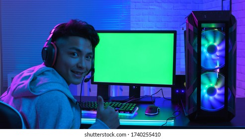 E Cyber Sport Gamer Has Thumb Up Gesture And Smile To You In Front Of Green Screen Monitor With Powerful Personal Computer On The Table At Home