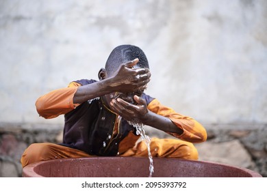 Eager Little Black African Boy Sitting In Front Of A Tub Vigorously Washing His Face; Personal Hygiene In Children Concept