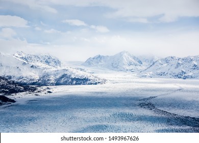 Eagle Peak, Alaska - April 10, 2017: An extreme wide aerial view of Eagle Peak mountains in Alaska with cloudy shades crossing the frozen lake