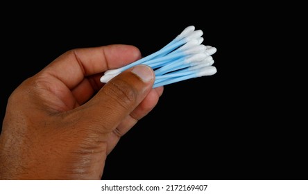 ear cleaning buds showing by hand on black background, cotton ear wax cleaning buds holding on dark background