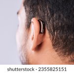 Ear, deaf and hearing aid closeup in studio on a gray background for sound, audio or communication. Technology, listening and a man with a disability closeup for implant or medical innovation