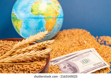 An Ear And A Grain Of Wheat Against The Background Of A Dollar Bill And A Globe Of The Earth. The Concept Of Harvesting, Exporting, Importing, Drought In Hot Countries. Lack Of Bread.