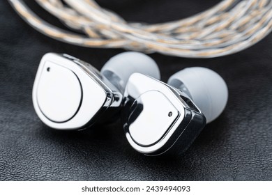 In ear monitor on a tablature background. Custom in-ear monitors with black plates. Custom in ear monitors or IEMs ready for a musician to wear on stage at a concert.	
					