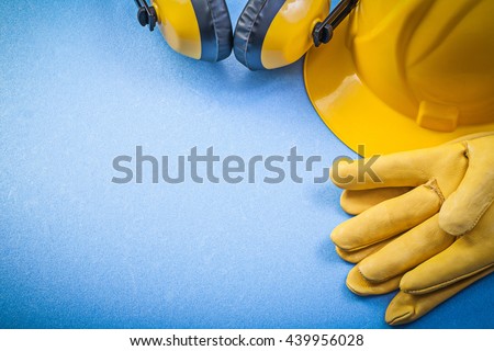 Ear muffs leather safety gloves building helmet on blue background construction concept.