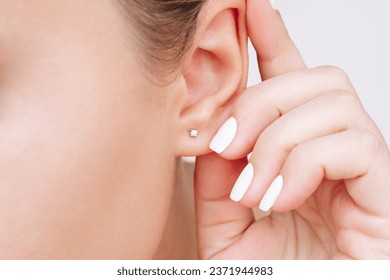 Ear piercing. Cropped shot of a young woman wearing elegant stud earrings. Jewelry with gemstones, accessories - Shutterstock ID 2371944983