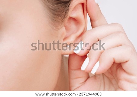 Ear piercing. Cropped shot of a young woman wearing elegant stud earrings. Jewelry with gemstones, accessories