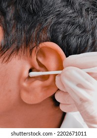 Ear Wax Cleaning With Swab Cotton Bud Sticks Hisopo By Ent Specialist Doctor Nurse With Gloves On Hands, Earwax Removal From Teen Boy's Ear Treatment Closeup View Image Photo