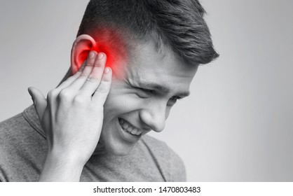Earache. Young man suffering from acute pain in ear, free space