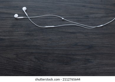 Earbuds On A Dark Wood Background With Copy Space