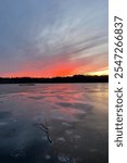 Early blue winter ice along lake below a cold red sunset