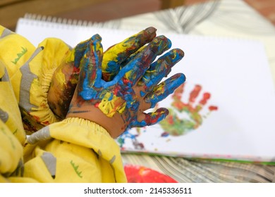 Early Childhood Development Activity: Finger Painting Outside On A Sunny Day. Close-up Of A Child's Fingers Covered With Bright Colourful Paints.