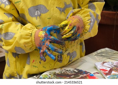 Early Childhood Development Activity: Finger Painting Outside On A Sunny Day. Close-up Of A Child's Fingers Covered With Bright Colourful Paints.