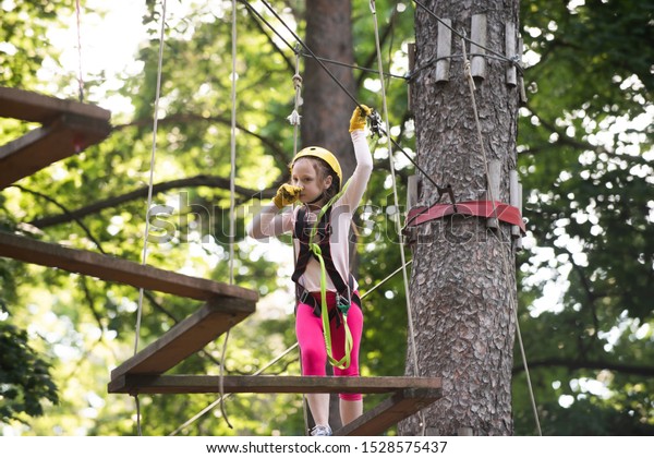 Early childhood
development. Teenager girl adventure and travel. Toddler climbing
in a rope playground structure. Toddler kindergarten. Balance beam
and rope bridges