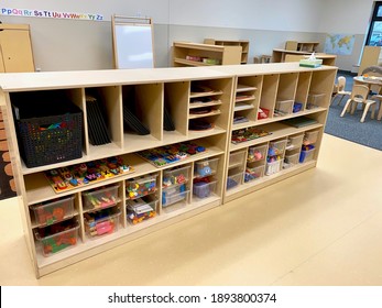 Early Childhood Education Preschool Classroom. Tables With Art, Chairs, And Wooden Shelves With Supplies In Clear Bins. No People. 