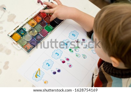 Early education, learning to count. 2 year old boy puts correct amount of stamps to assigned number. children, people, infancy and education concept. formation and development of the child.