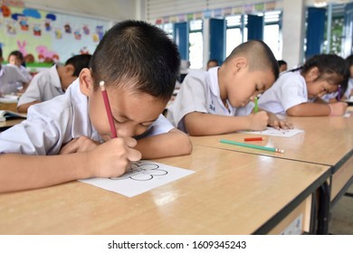 Early Elementary School Children In Thai Student Uniform Are Intending To Make Work Sheets In The Classroom.