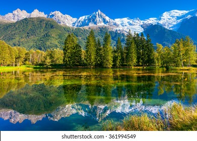 Early fall in Shamoni,  France. The snow-covered Alps and evergreen fir-trees are reflected in lake - Powered by Shutterstock