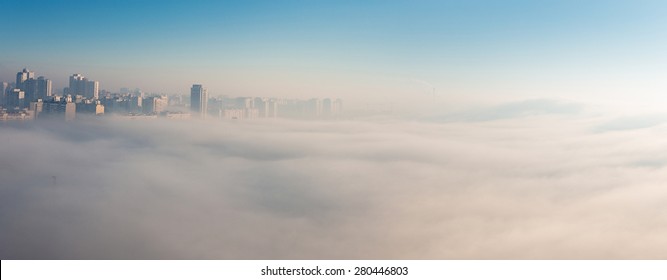 Early Foggy Morning Over The City. Dense Fog Envelops The Residential Area. Buildings Sticking Out Of The Fog. Wide Panorama. Soft Focus